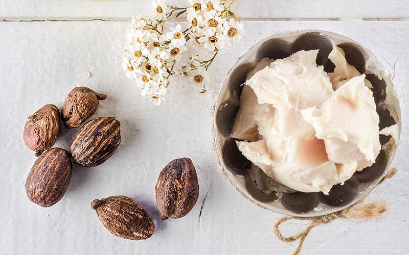 Shea nuts and shea butter in a bowl on a table.