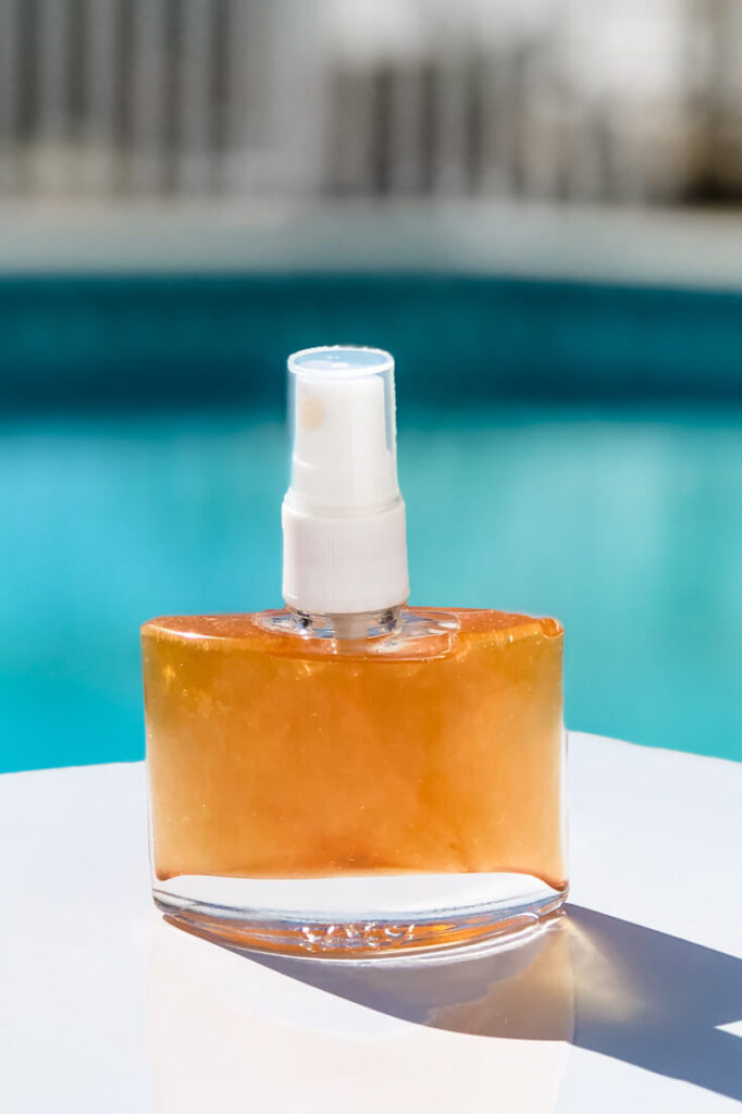 Spray bottle of diy shimmer body oil on table